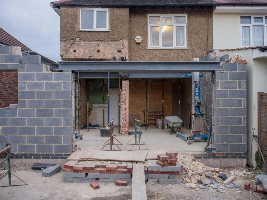 Masonry rear extension taking shape behind a family home