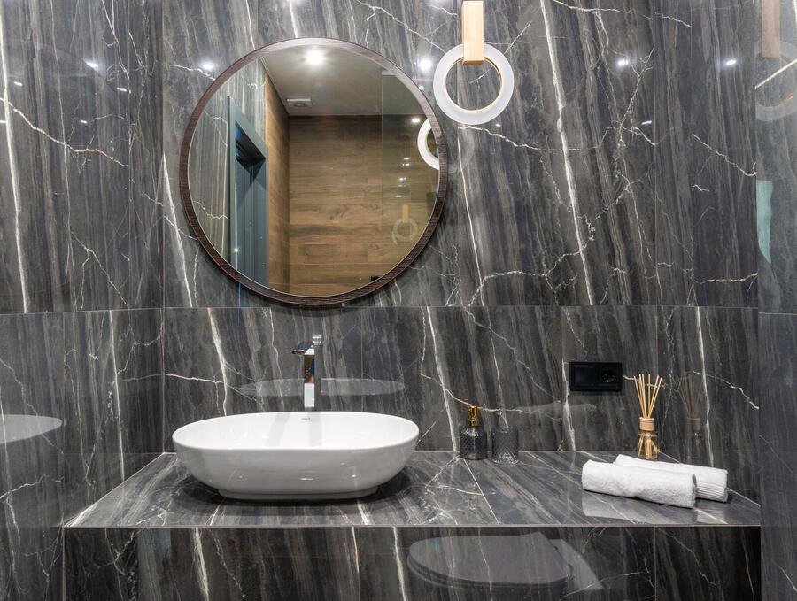 Luxury bathroom with black marble, round mirror and vessel sink