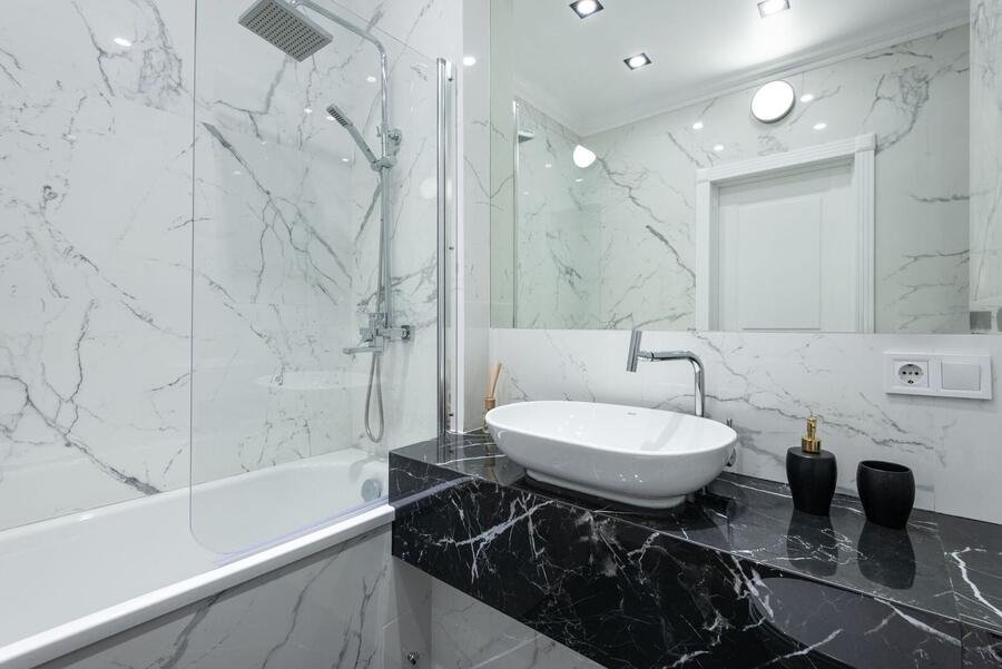 Bright marble bathroom with freestanding tub and black vanity