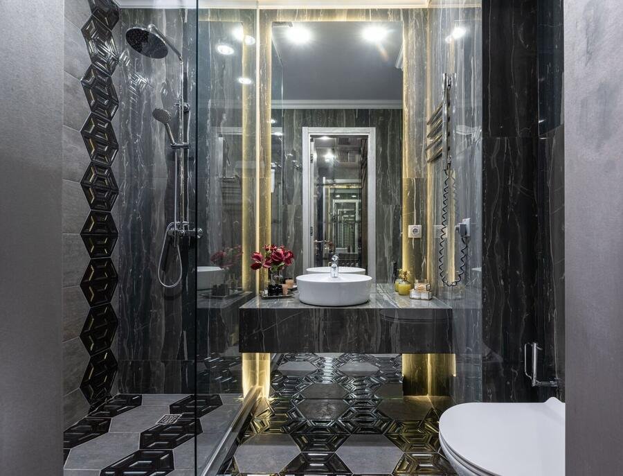 Dark luxury bathroom with gold accents and glass shower