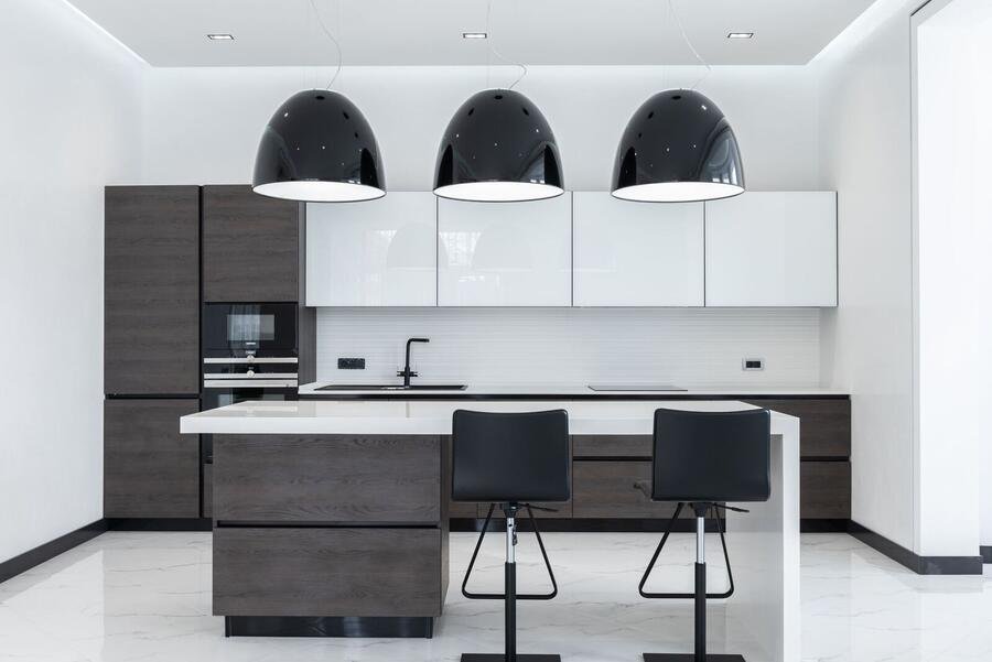 Luxury kitchen with dark cabinetry, white island and pendant lighting