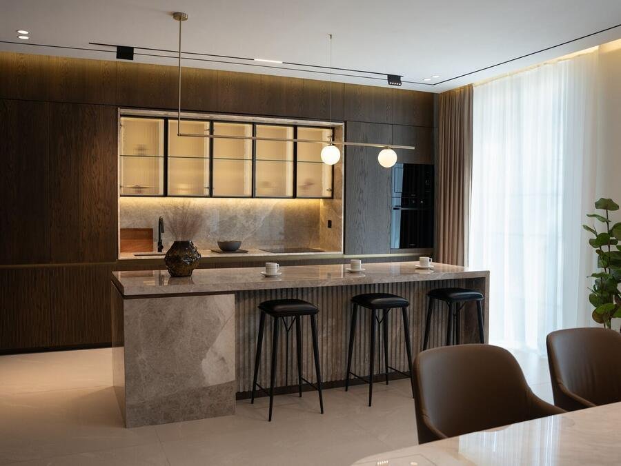 Contemporary kitchen with dark island and statement lighting